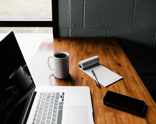 A clean workspace desk with a laptop closed and a cup of tea